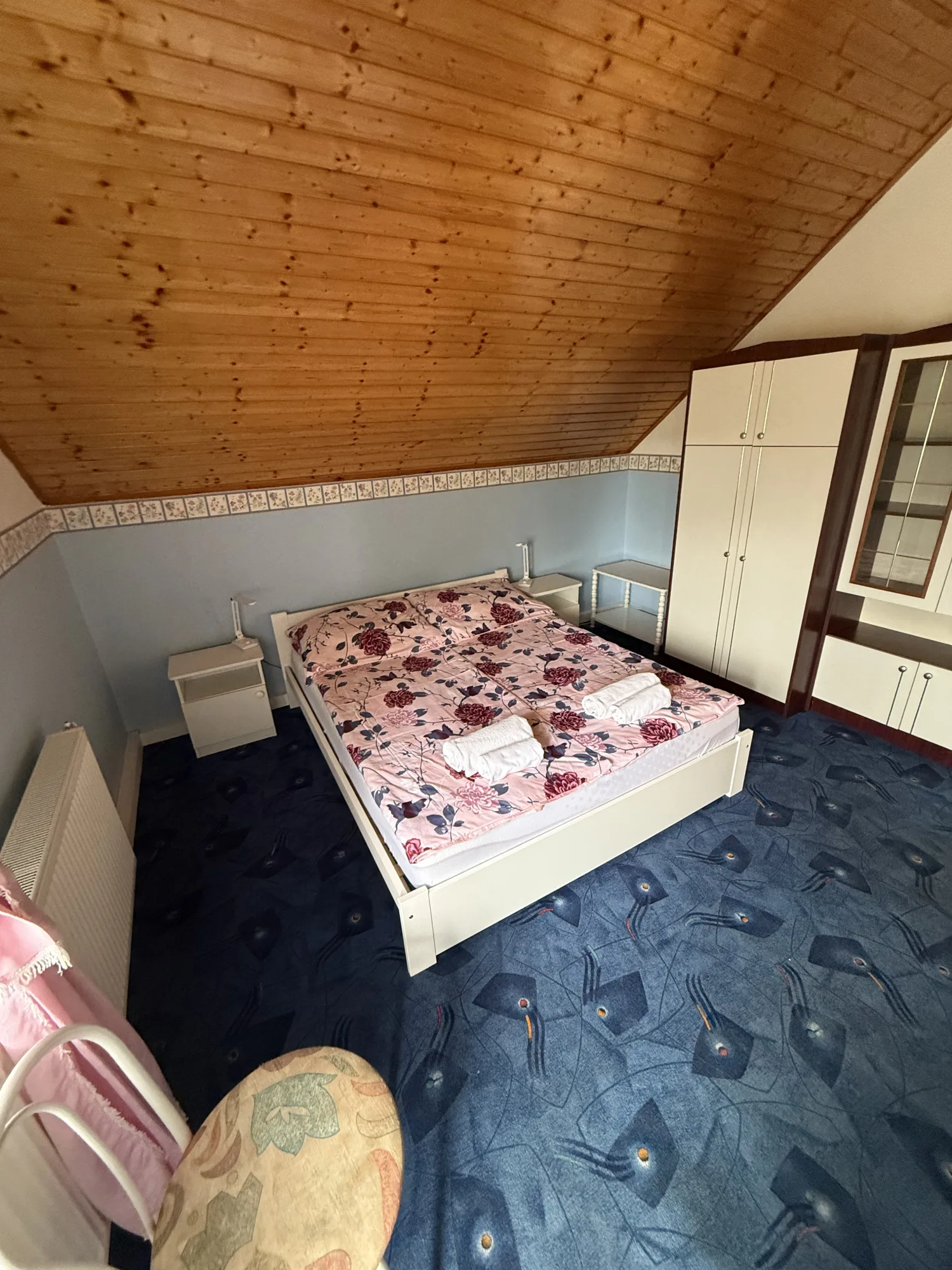 Tágas tetőtéri hálószoba a Beáta Apartmanházban franciaággyal és ruhásszekrénnyel